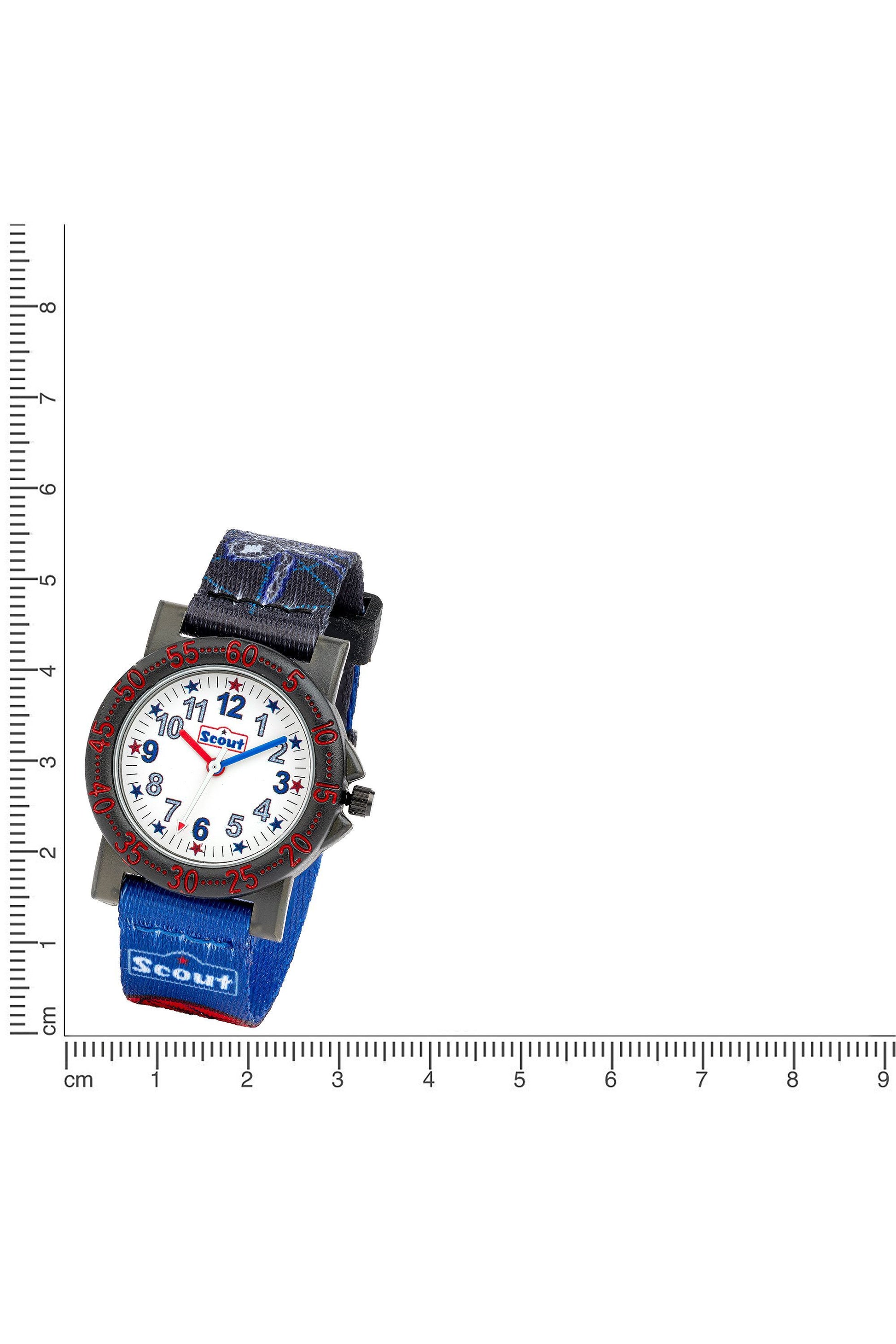Scout Kinderuhr mit blau-schwarzem Textilband, Fledermaus- und Spinnen-Motiven sowie Lernzifferblatt neben einem Lineal zur Größendarstellung
